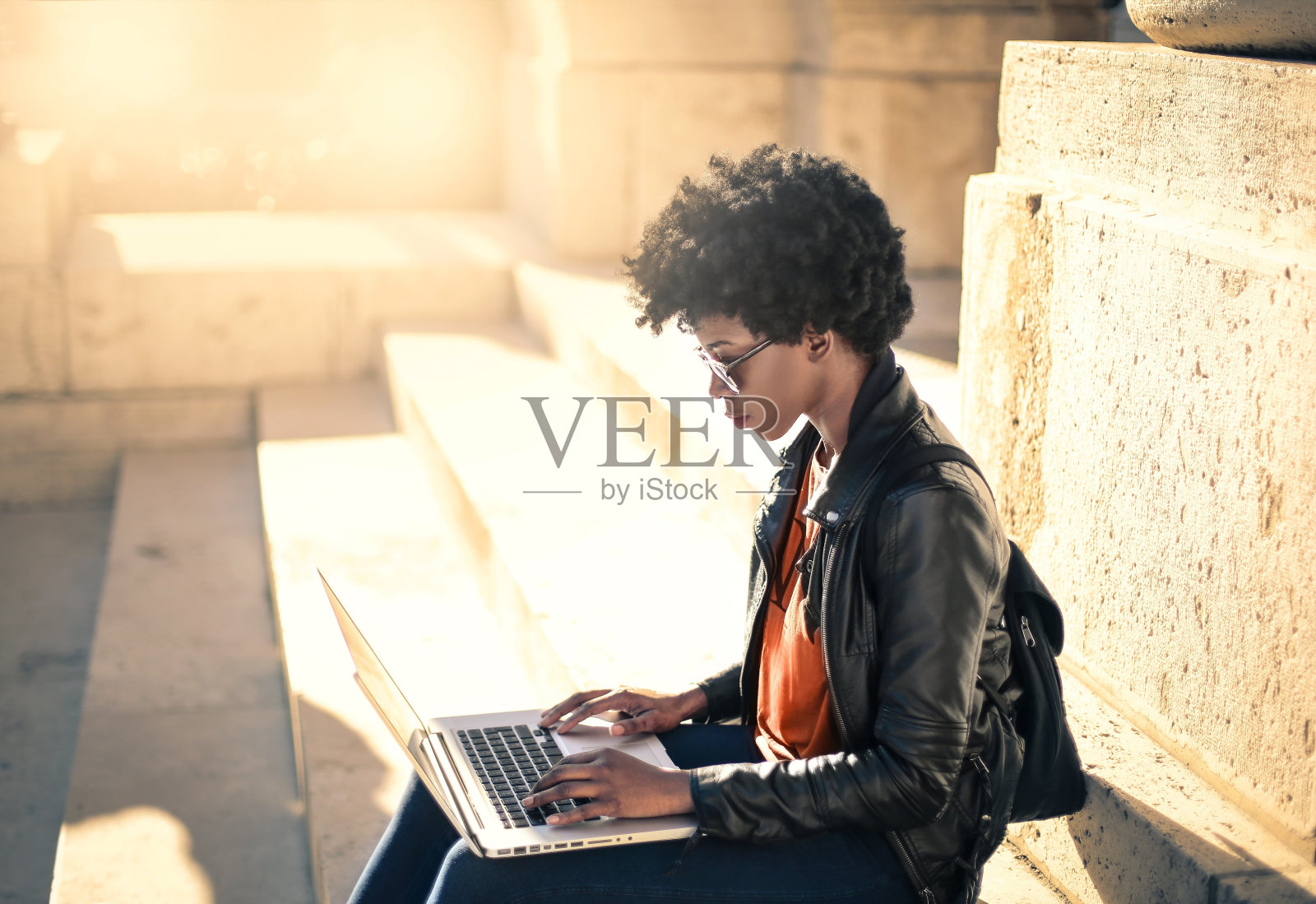 一位年轻的黑人女性坐在外面的楼梯上，用笔记本电脑专心工作照片摄影图片