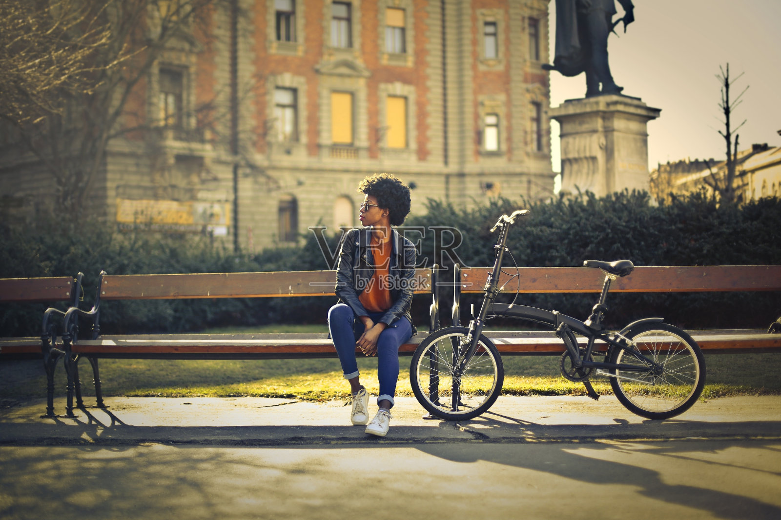 年轻的黑人女性坐在公园的长椅上等人照片摄影图片