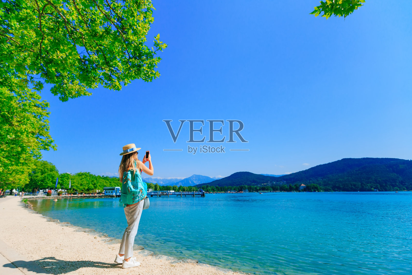 一个背着背包的女孩和一个划船的人在湖边。gi照片摄影图片