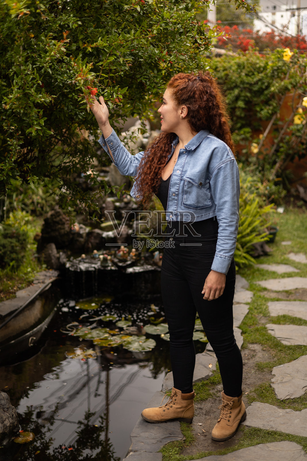 欣赏花园自然的一位卷头发的年轻女子，白天穿着休闲的衣服，生活方式照片摄影图片