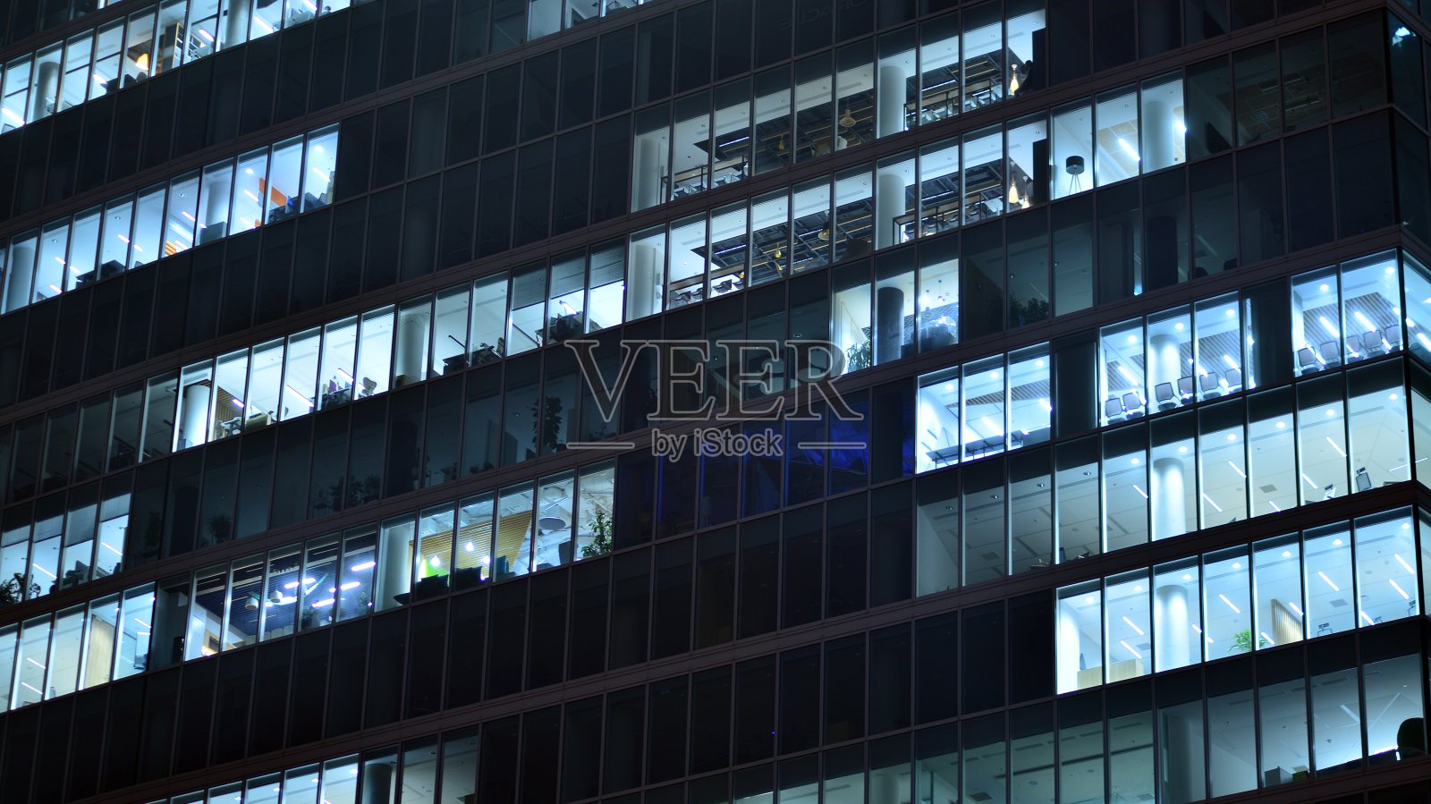 城市中现代化的办公大楼在夜晚。公司建筑的照明办公室视图。照片摄影图片