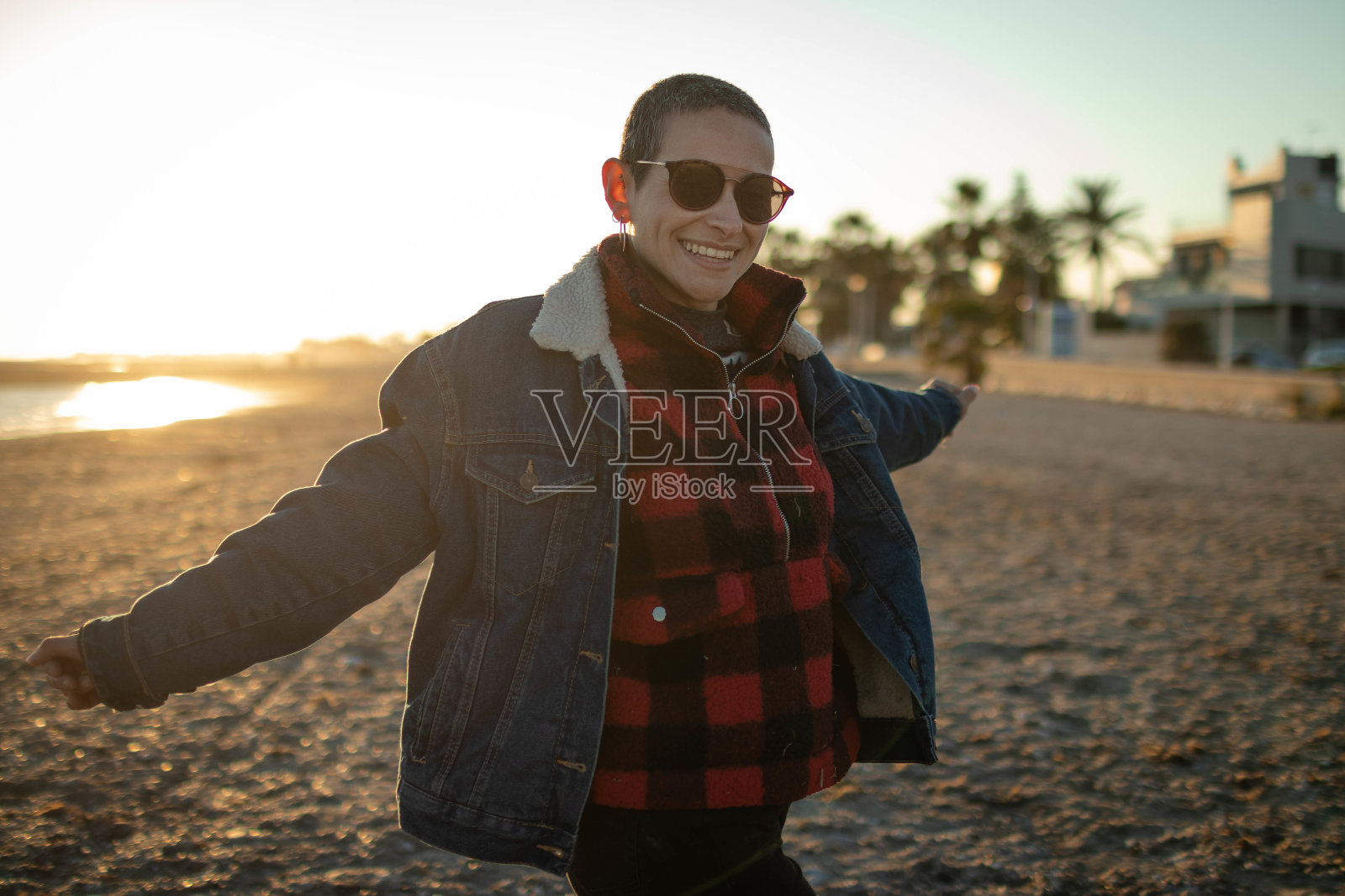 浅焦点镜头的女性墨镜和短发享受风景日落在海滩照片摄影图片