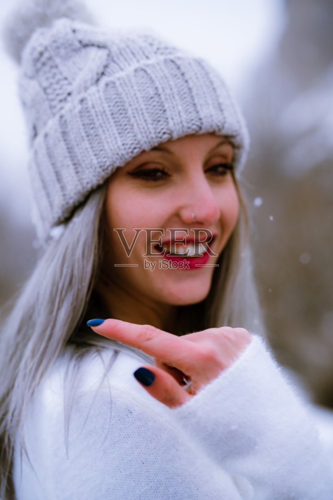 年轻的白人女孩戴着帽子，在雪天快乐地摆姿势照片摄影图片