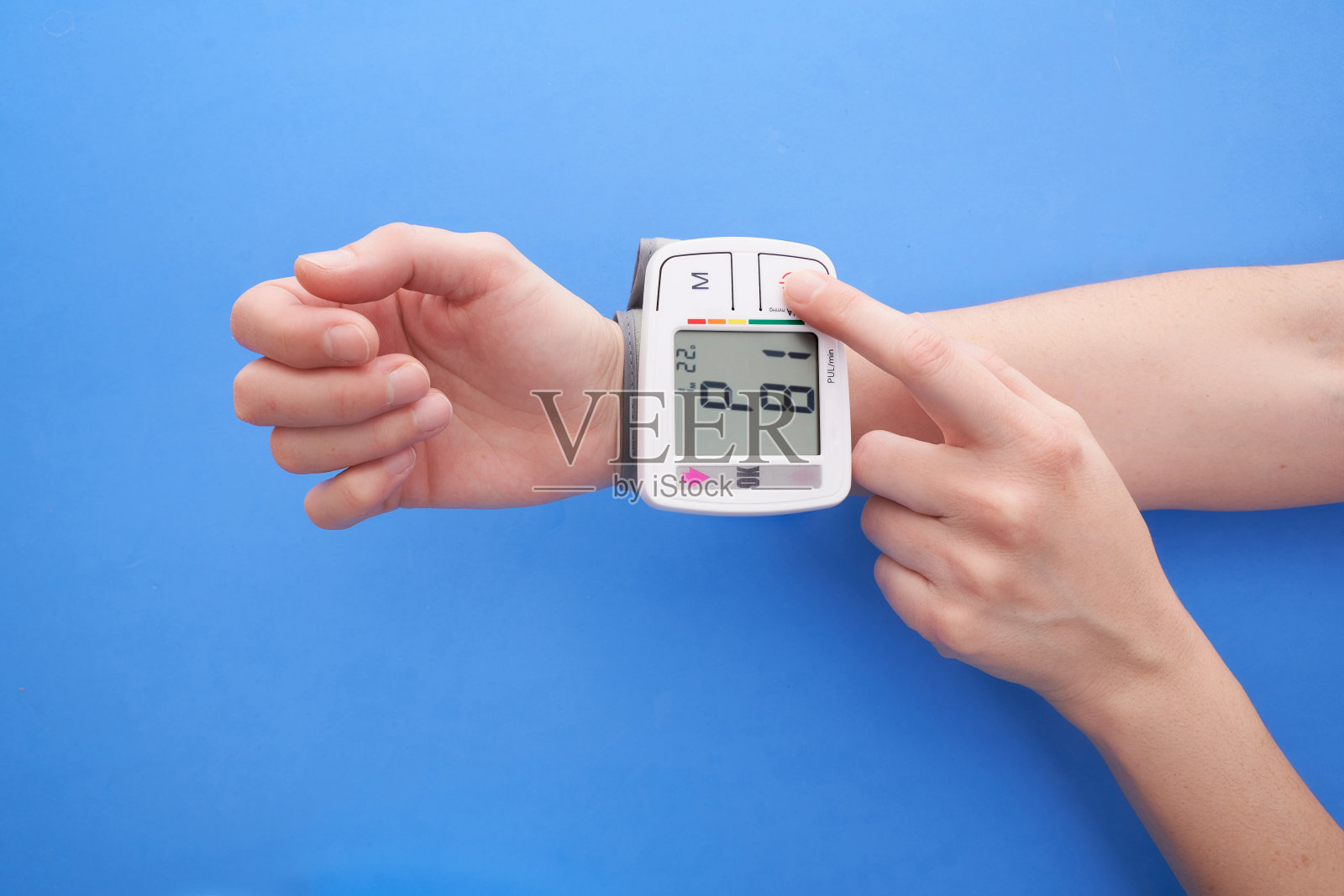 用蓝色背景的血压计测量自己的血压照片摄影图片