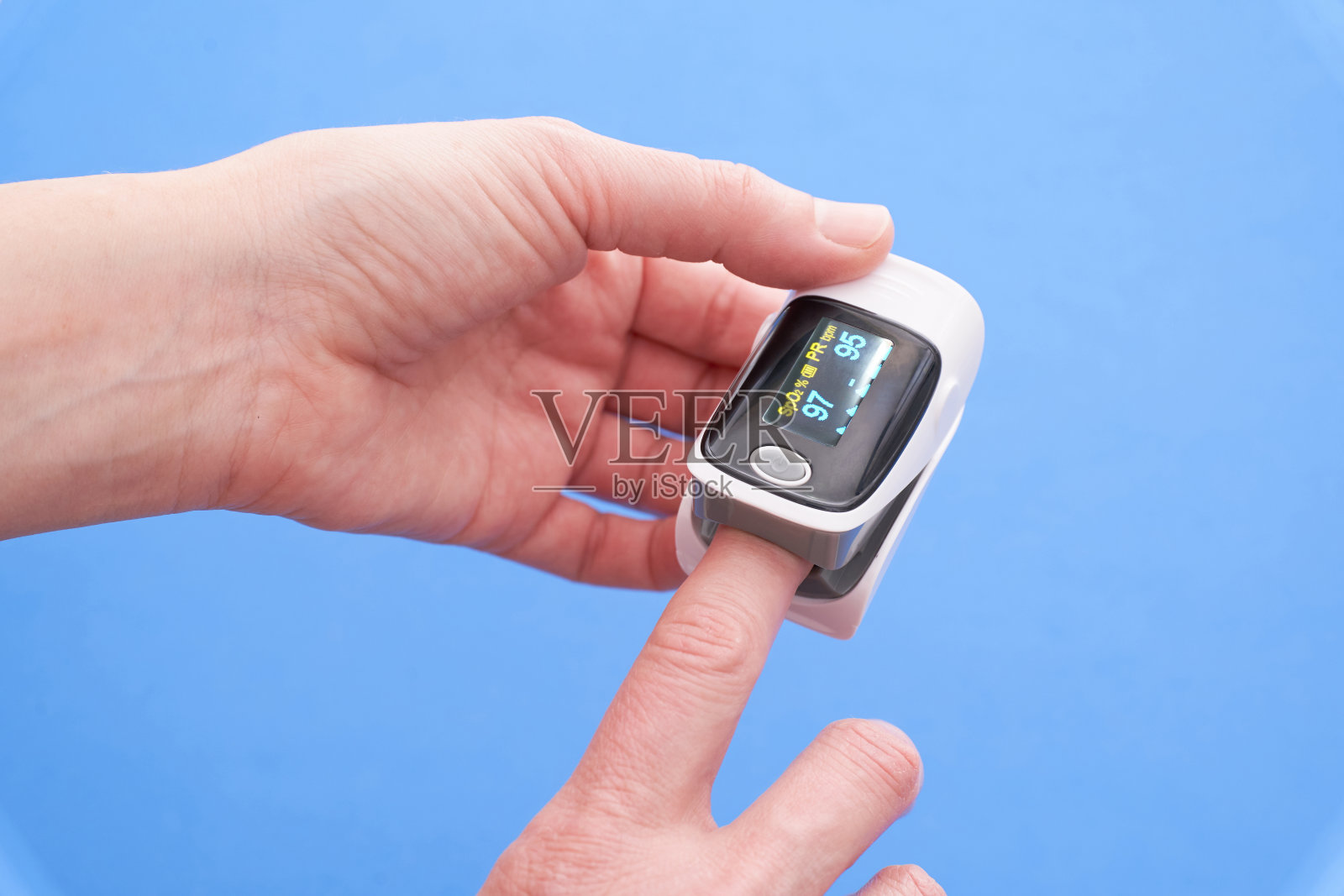 手指上的脉搏血氧计在蓝色背景上照片摄影图片