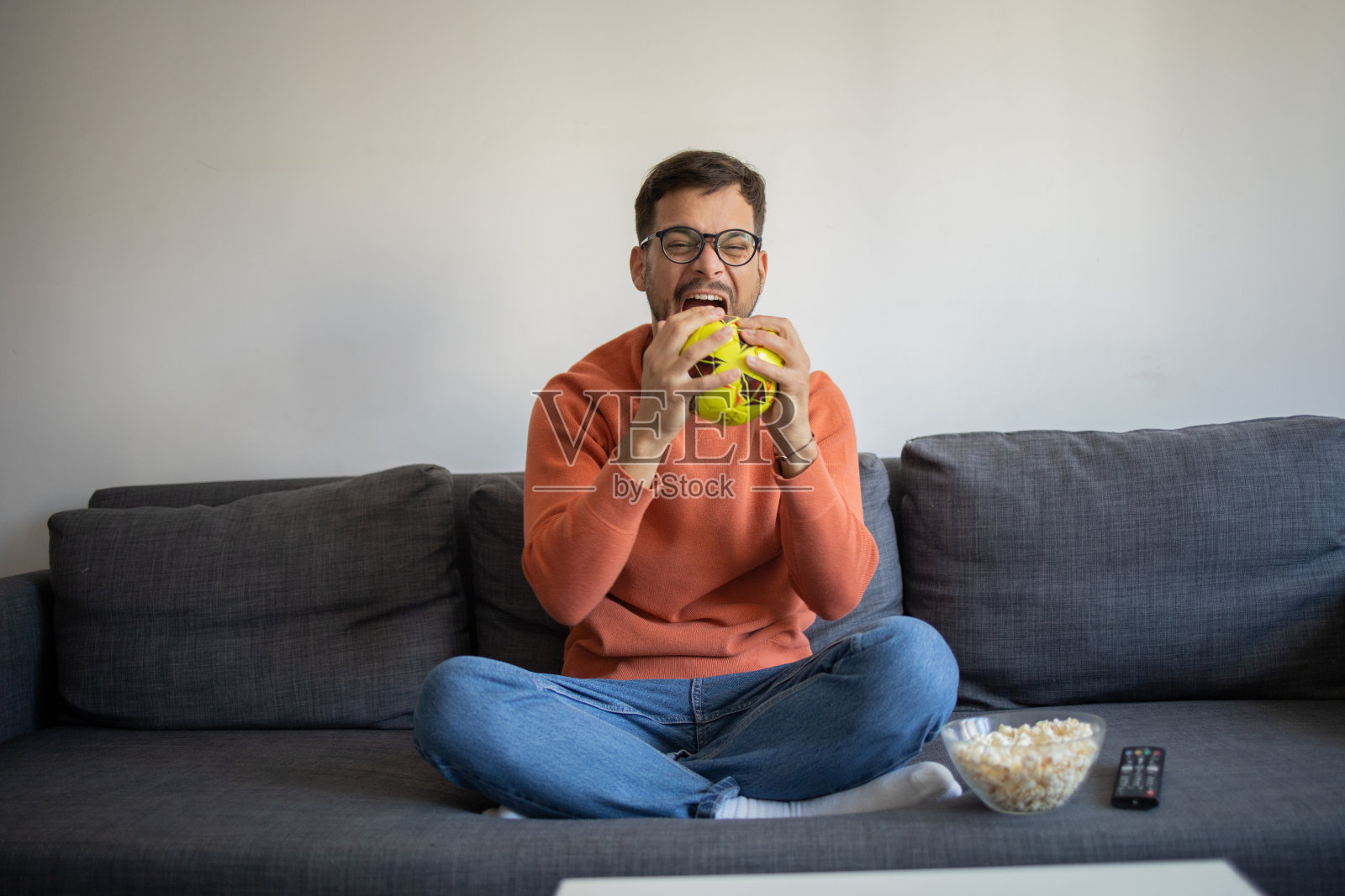 兴奋的男子在家里看电视时欢呼照片摄影图片