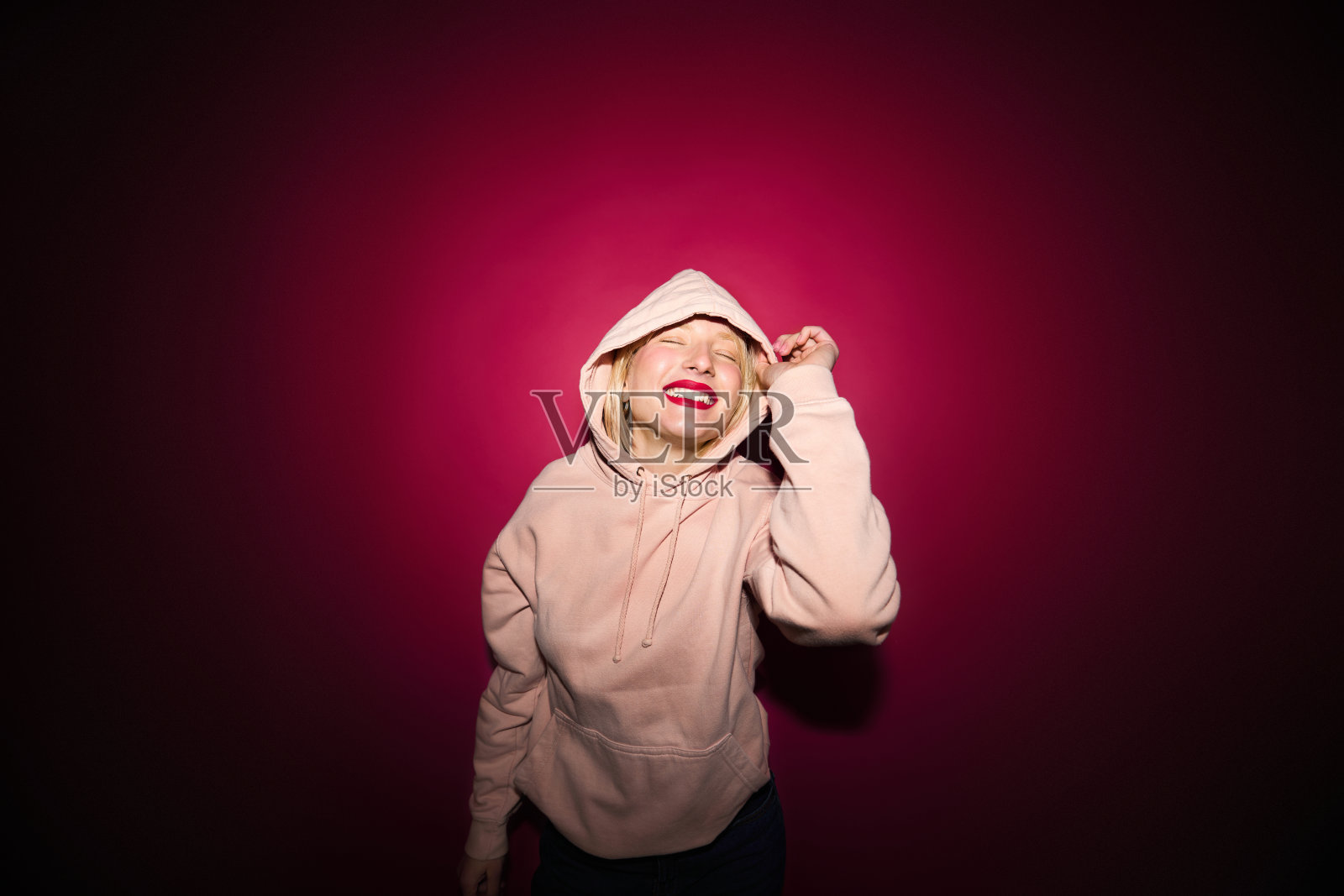 肖像的一个快乐的女孩笑着，在洋红色的背景上孤立地摆姿势。洋红色万岁，年度流行色。照片摄影图片