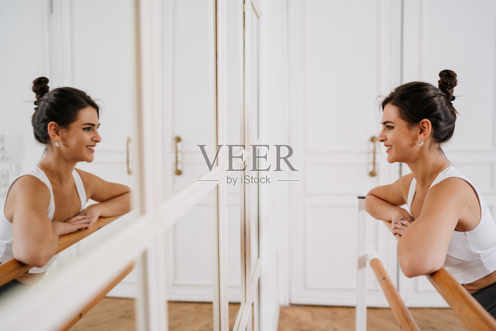 漂亮的西班牙女孩站在镜子微笑靠在芭蕾舞吧台在舞蹈课上微笑满意的成就。年轻漂亮的女人很高兴能保持健康。
健身，有目标的人。照片摄影图片