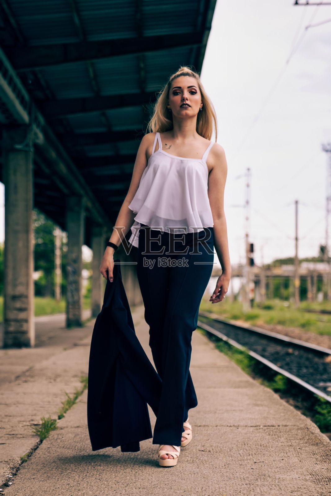 时尚的年轻金发女子在专业服装走在站台上照片摄影图片