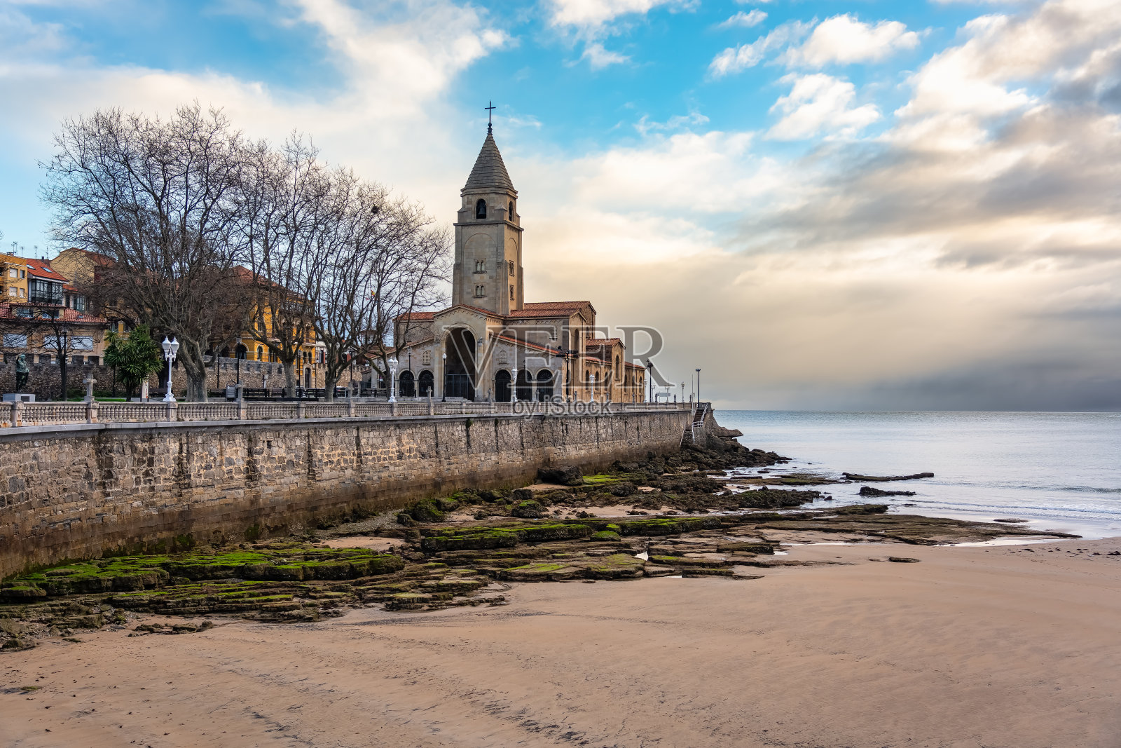 位于西班牙海滨城市希洪海滩上的圣佩德罗教堂旁边的壮观日出。照片摄影图片