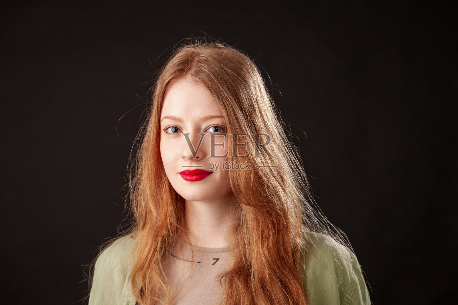 一个迷人的年轻红头发女人的特写照片，在黑色的背景上涂着红色的口红照片摄影图片