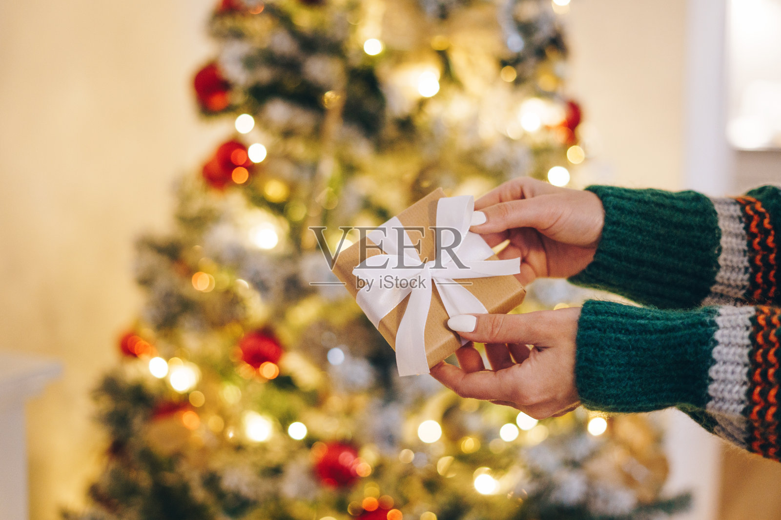 一名女子拿着礼物站在装饰好的圣诞树前照片摄影图片