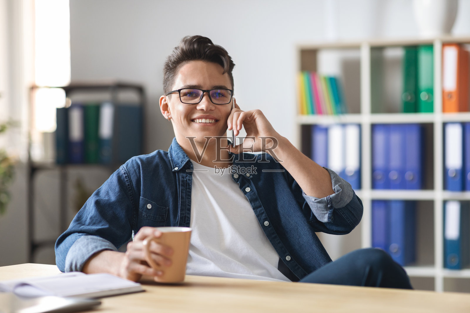 英俊的年轻人在办公室喝咖啡休息时间打电话照片摄影图片