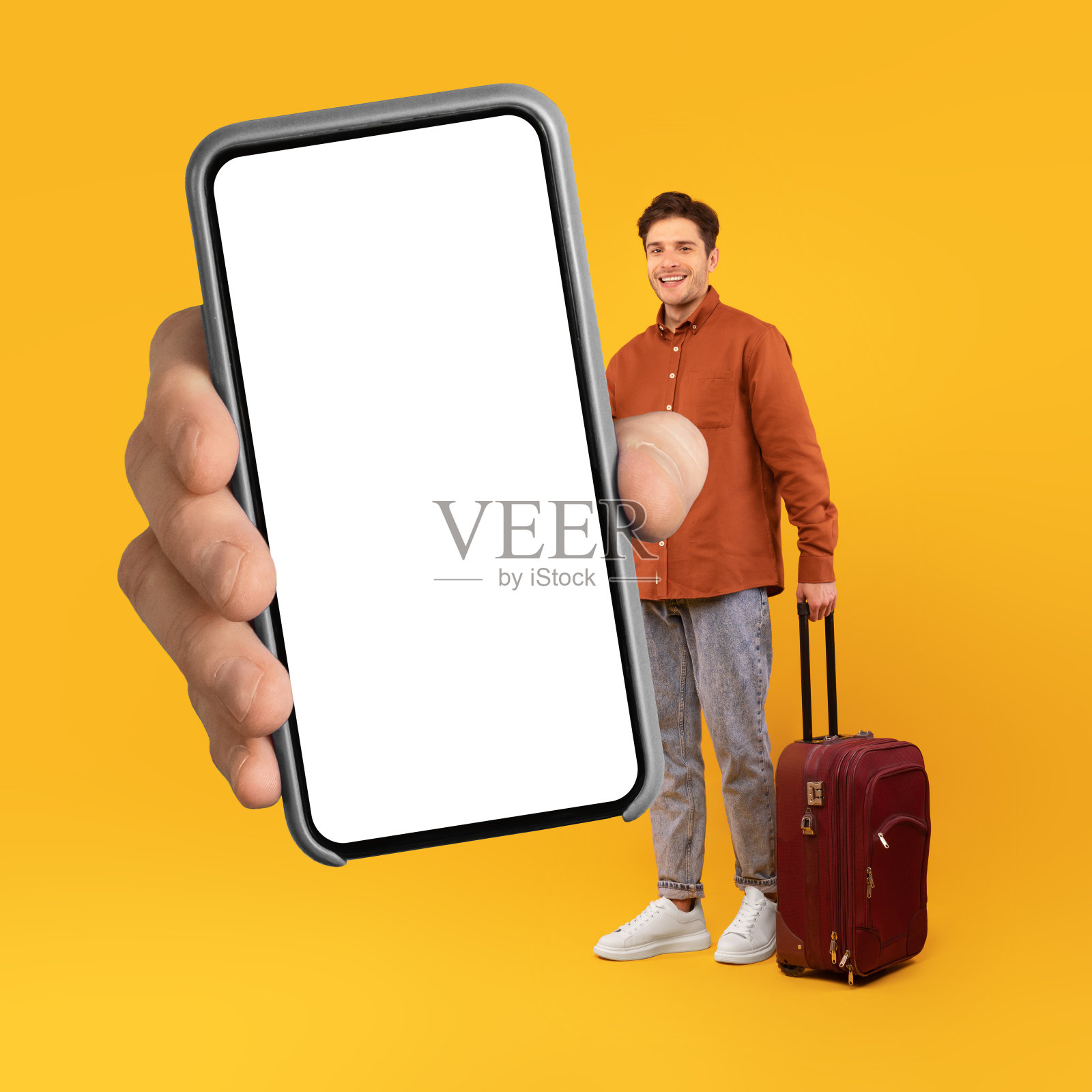 男性游客展示大手机，空屏幕，黄色背景照片摄影图片