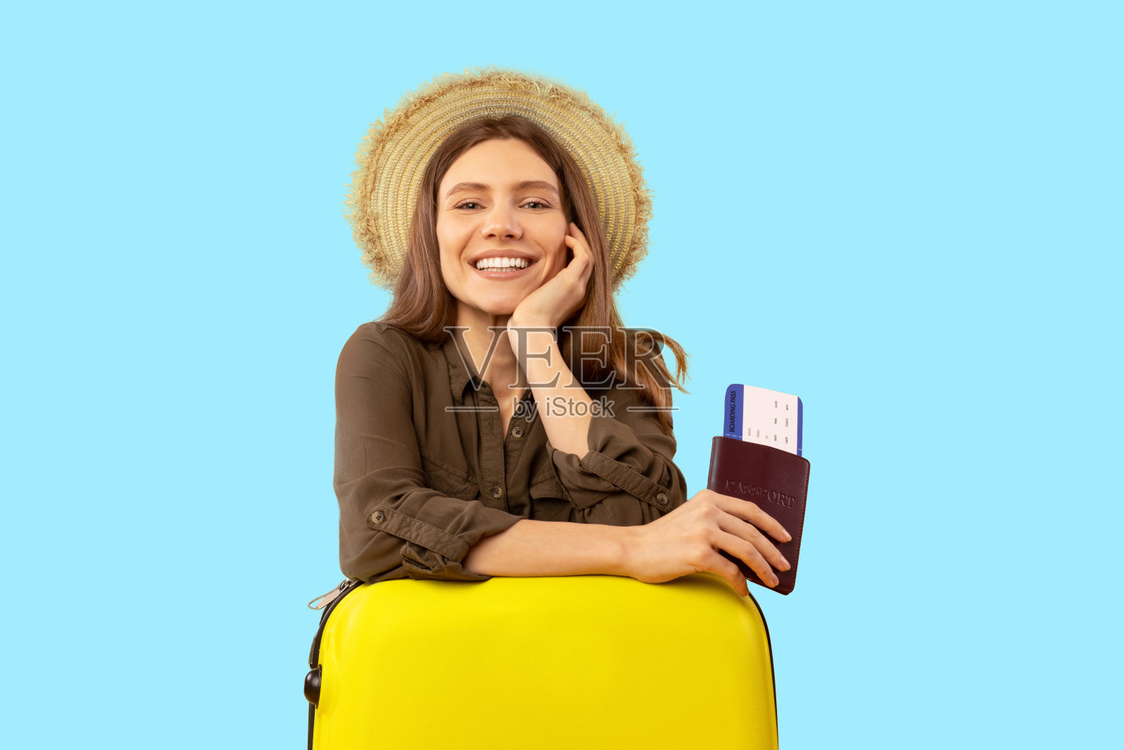 开朗的旅游女士摆姿势，持有蓝色背景的旅游门票照片摄影图片