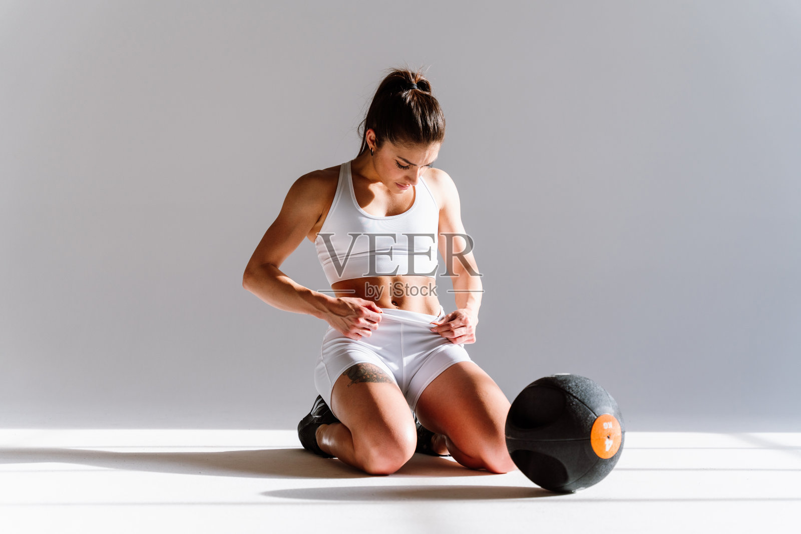 年轻的女运动员在健身房使用运动器材训练照片摄影图片