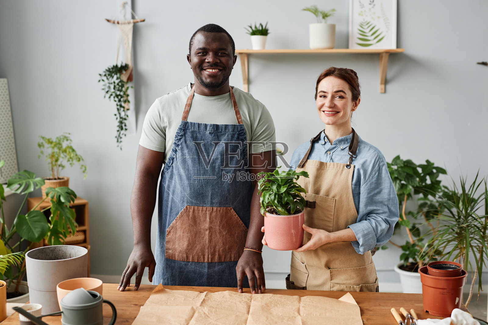 两个微笑的园丁看着镜头在室内照顾植物照片摄影图片