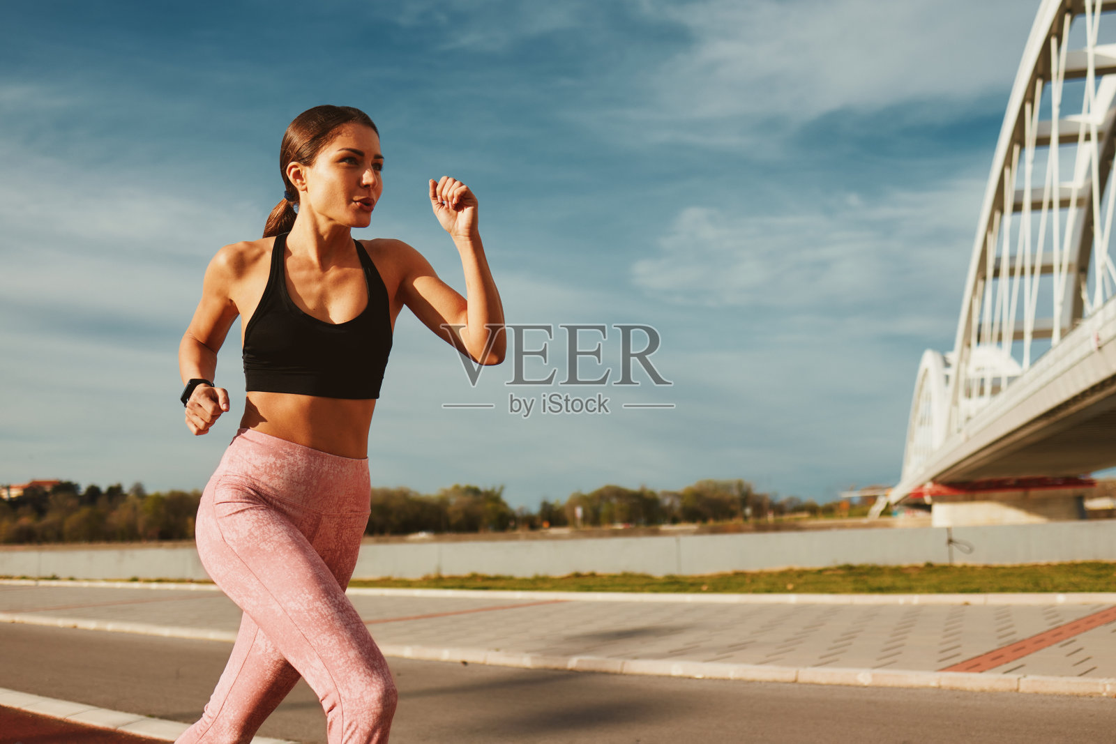 年轻的健身女子在河边和桥旁的小路上跑步照片摄影图片