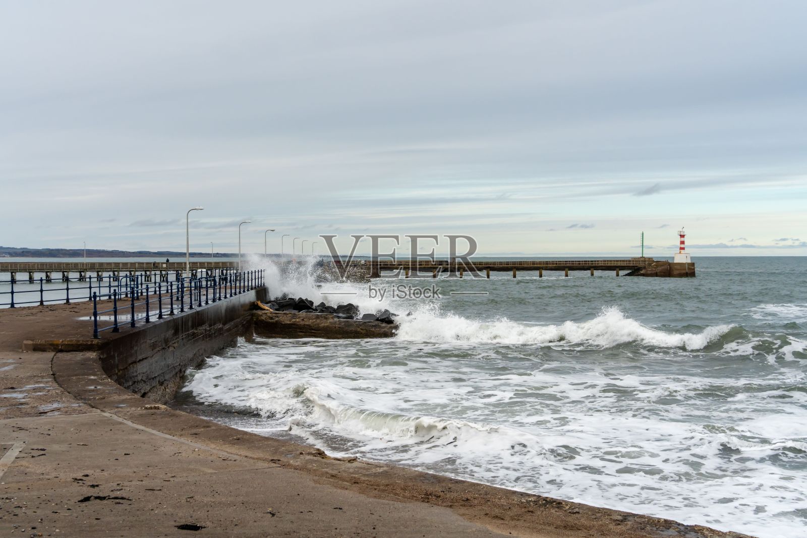 在英国诺森伯兰郡安布尔，海浪撞击海港墙的景象。照片摄影图片