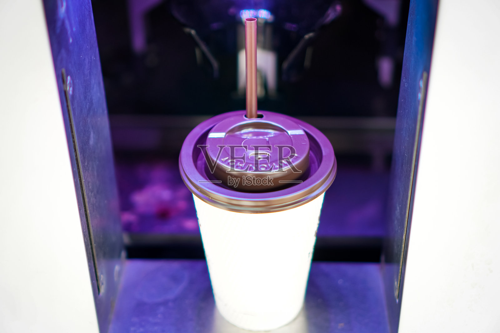 这张照片显示的是一杯热咖啡，咖啡管从饮料自动售货机里伸出来。照片摄影图片