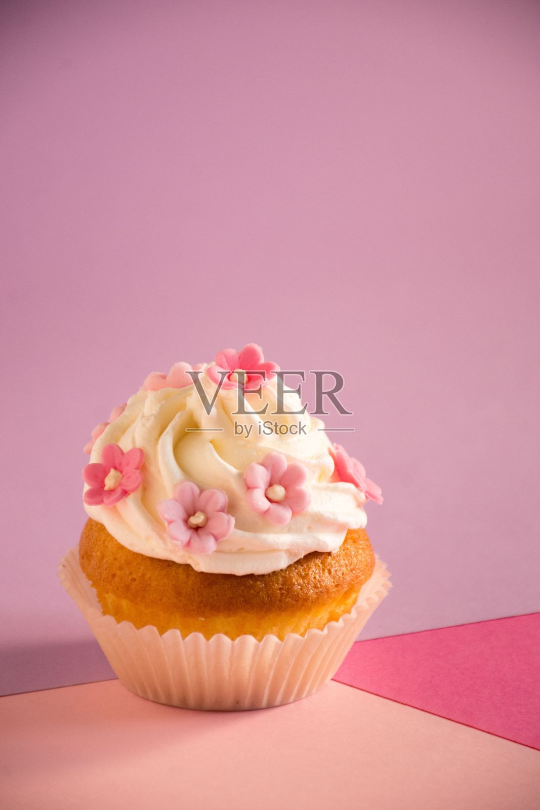 粉红色的糖霜和点缀在粉红色表面上的装饰点缀，开胃的纸杯蛋糕照片摄影图片