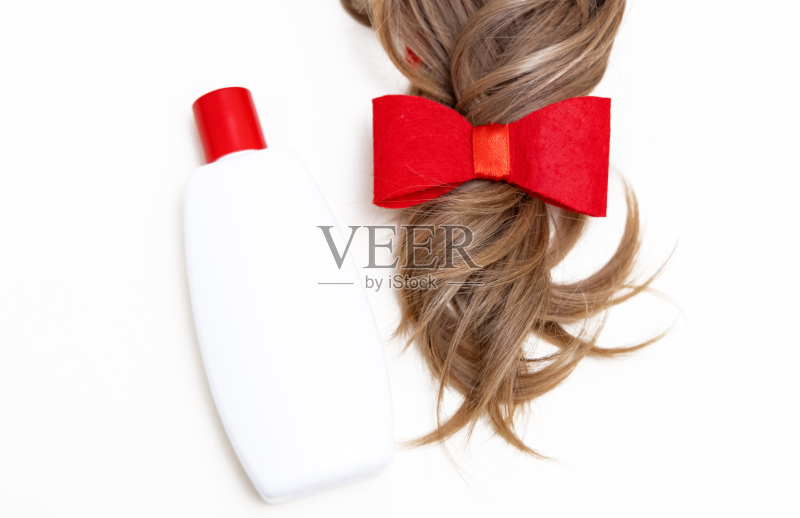 用护理产品或造型刷、烘干机或卷发棒隔离头发。红色蝴蝶结的头发照片摄影图片