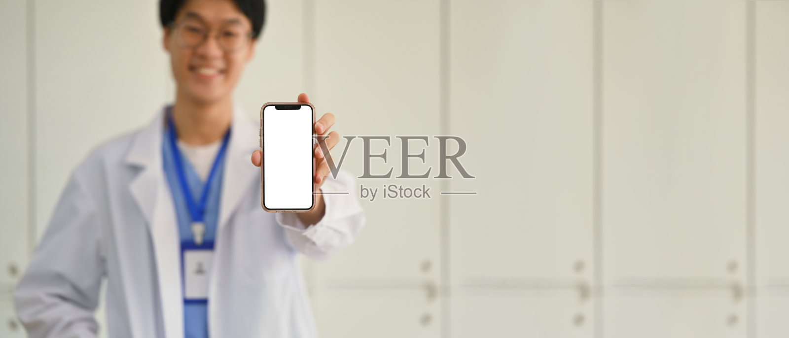 医生穿着白色制服，展示空白屏幕的智能手机做广告。远程医疗在线应用概念。照片摄影图片