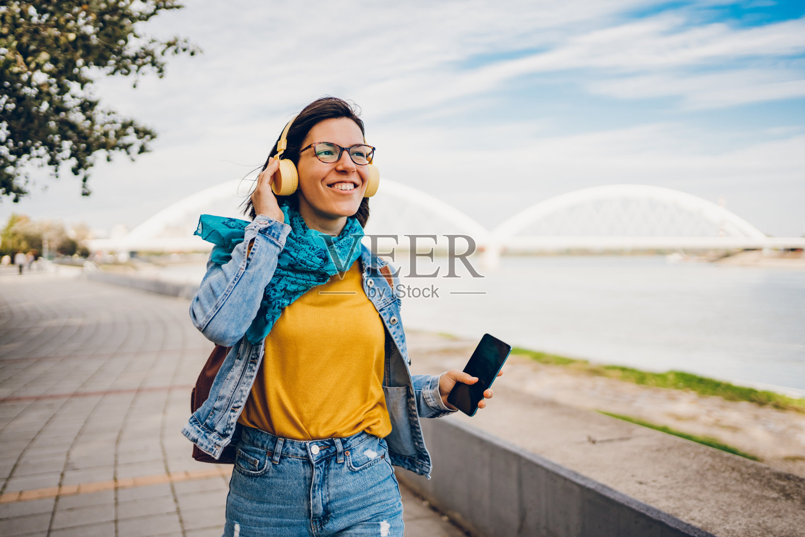 一位年轻女子走在码头边听音乐照片摄影图片