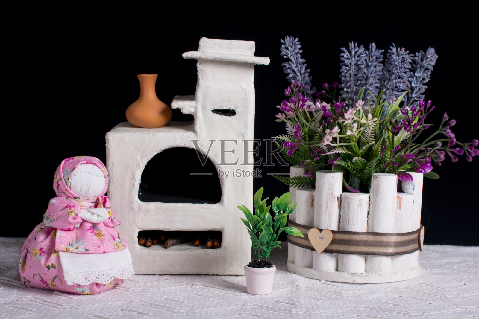 一束薰衣草和一个俄伯列兹尼萨娃娃。古色古香的白色火炉，黑色背景的手工布娃娃照片摄影图片