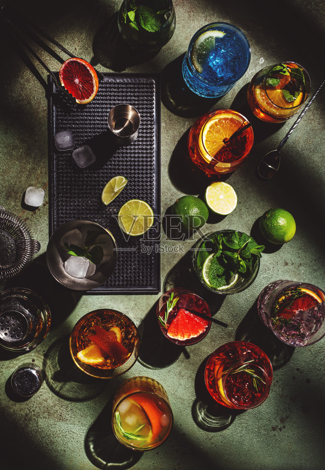 鸡尾酒设置在生锈的绿色吧台，俯视图。调酒术的概念。各种色彩丰富的烈性和低酒精饮料的夏季鸡尾酒会。深色背景，工具条，强光，俯视图照片摄影图片