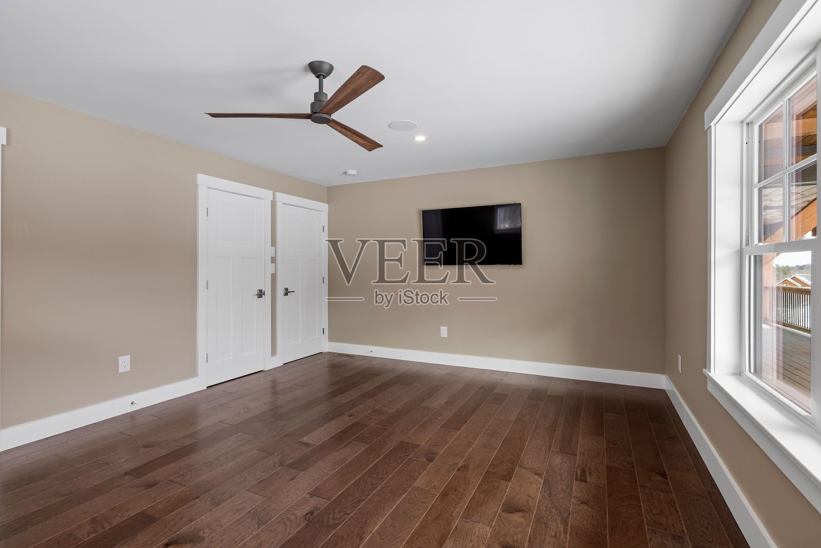 空房间，有吊扇，硬木地板和大窗户照片摄影图片