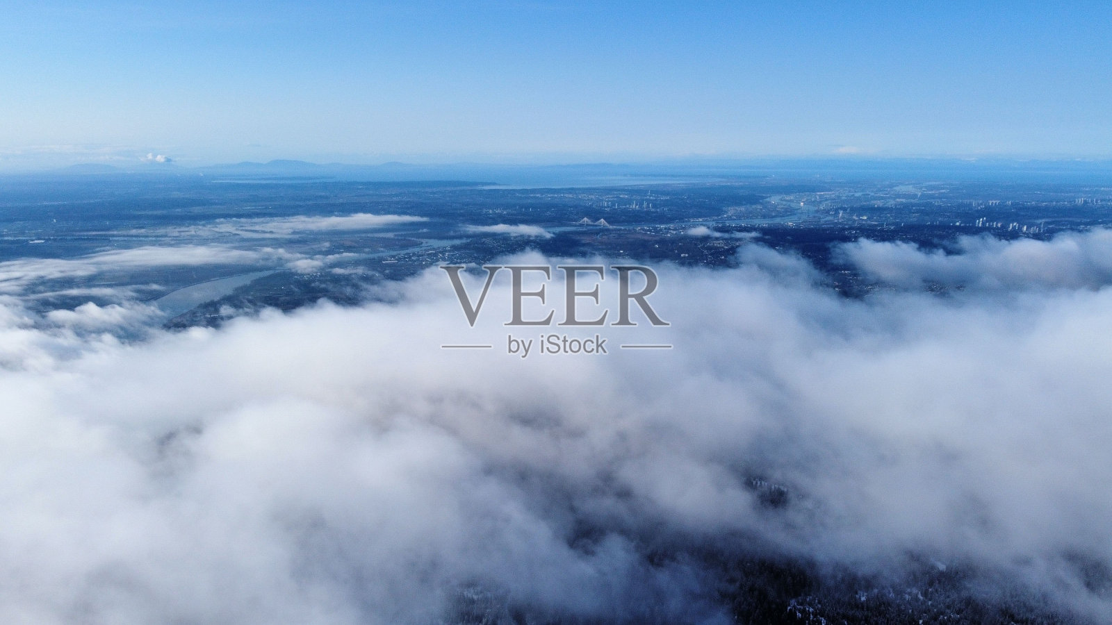 在阳光下，云层覆盖在茂密的树木上照片摄影图片