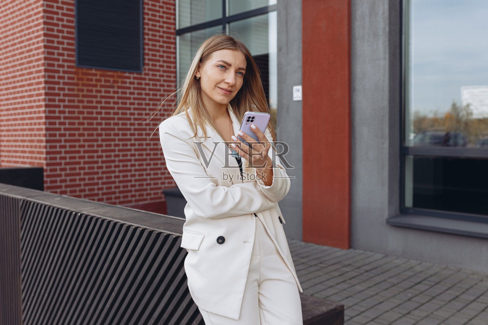 女企业家带着智能手机走在城市街头照片摄影图片