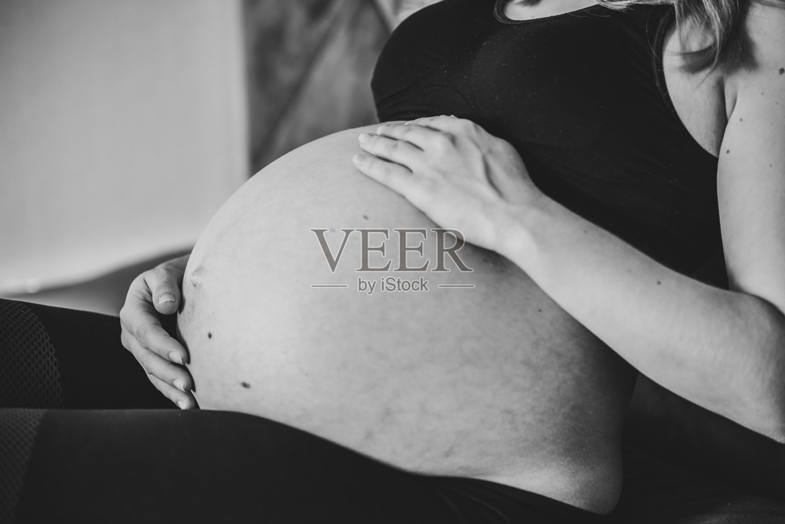 怀孕的女人。黑白照片。怀孕，母性，生育概念。女人的腹部特写。雌性等待新生婴儿。怀孕的女孩抚摸，抱着肚子，关心健康。照片摄影图片