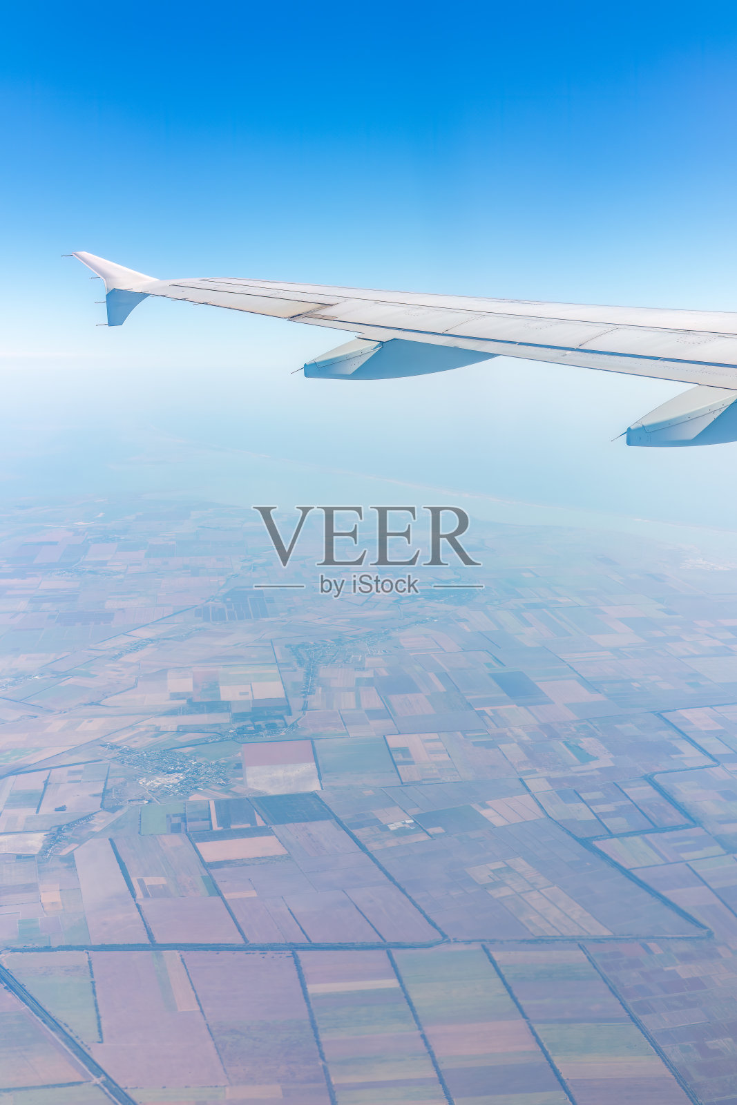 从绿色地面上的飞机窗口鸟瞰。从飞机窗口看到日出时美丽的云照片摄影图片