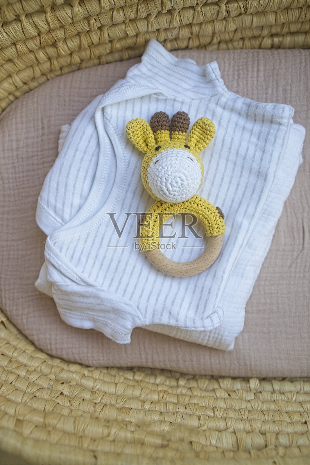 篮子里有给婴儿的东西，还有木制和针织的玩具——拨浪鼓。自然自然的简约风格。从高处俯瞰照片摄影图片