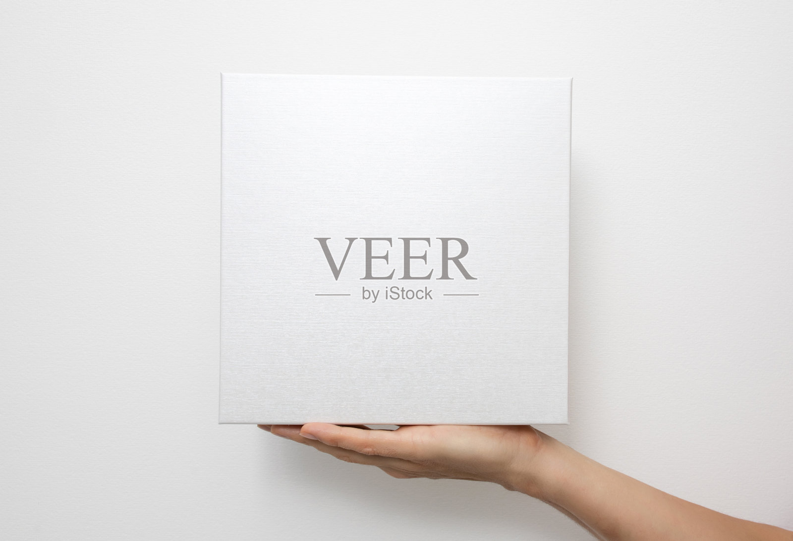 白色背景上的白色盒子模型。手握空白纸板礼物照片摄影图片