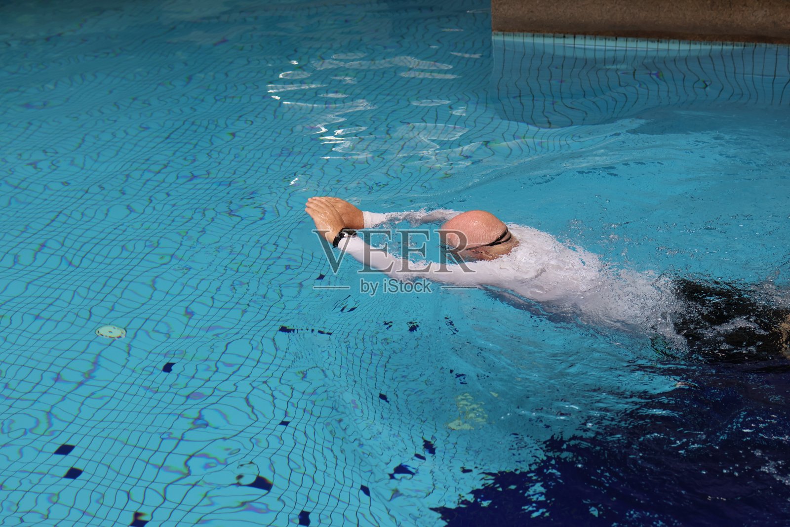 成熟的灰胡子男子在游泳池游泳时使用智能手表照片摄影图片