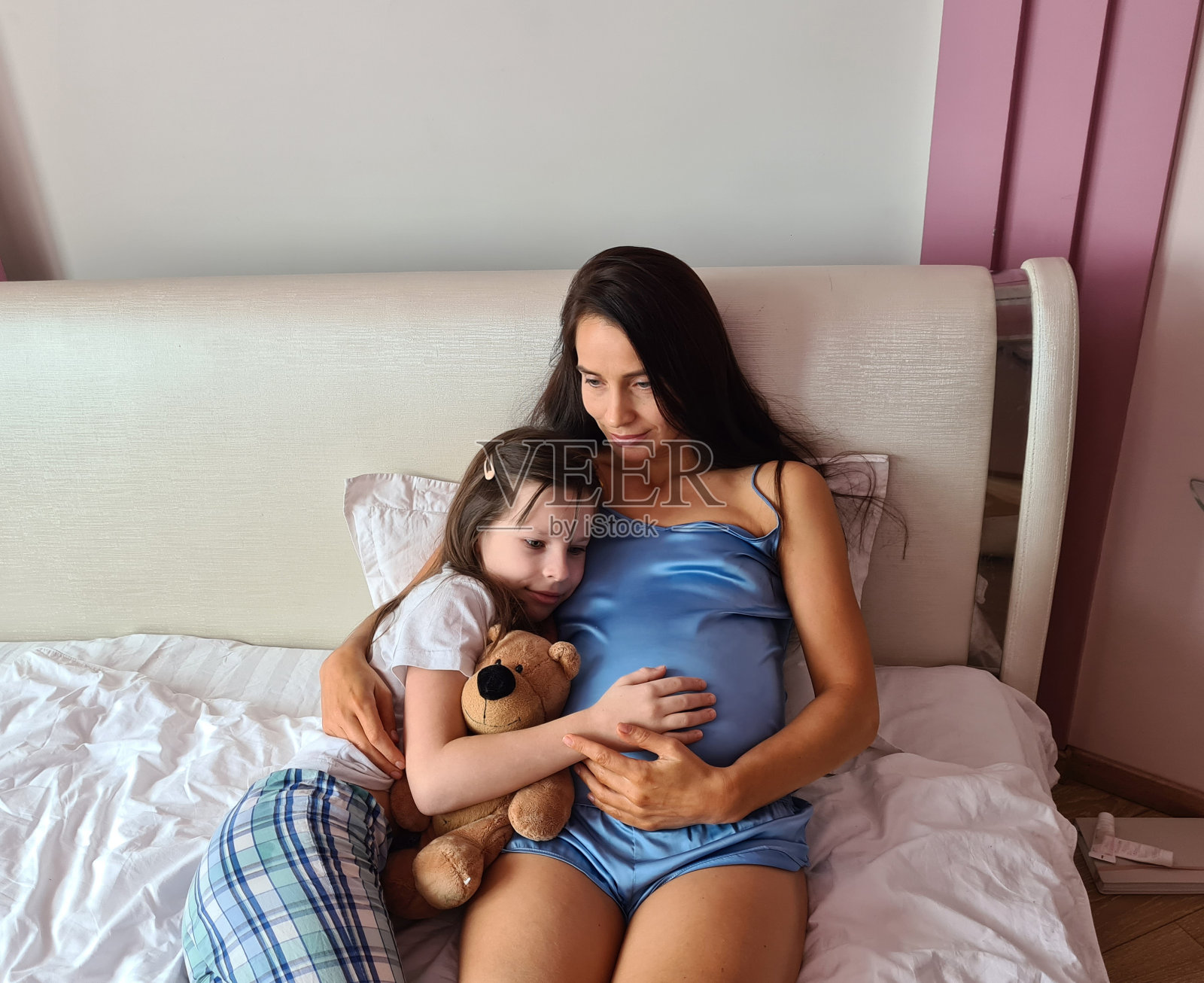 可爱的小女孩拥抱美丽的怀孕妈妈的肚子和微笑照片摄影图片