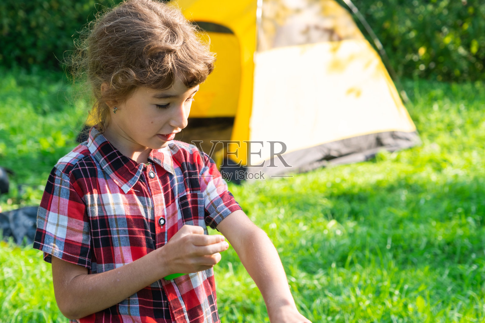 女孩在大自然中喷洒蚊子喷雾，叮咬她的手和脚。防止昆虫叮咬，对儿童安全的驱虫剂。户外娱乐，防止过敏。夏天的时间照片摄影图片