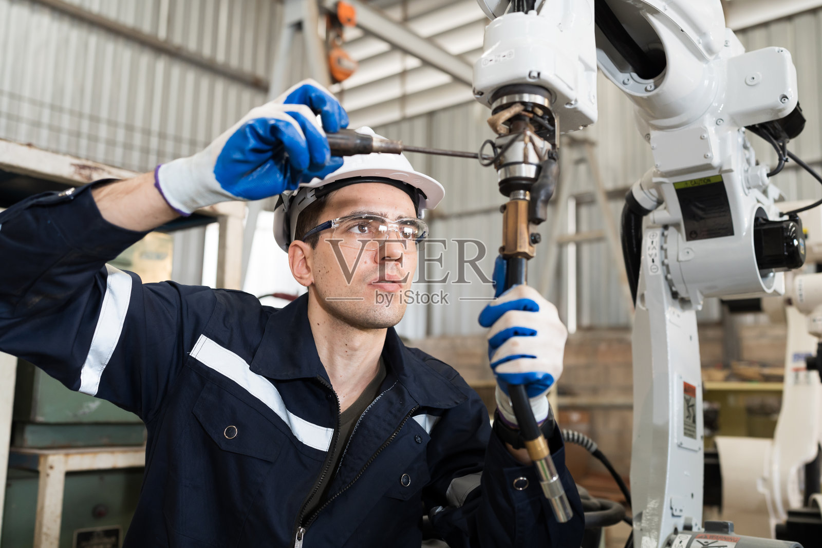 技术员在车间修理机械臂。负责工厂自动机械臂设备的维护。工业机器人制造技术照片摄影图片