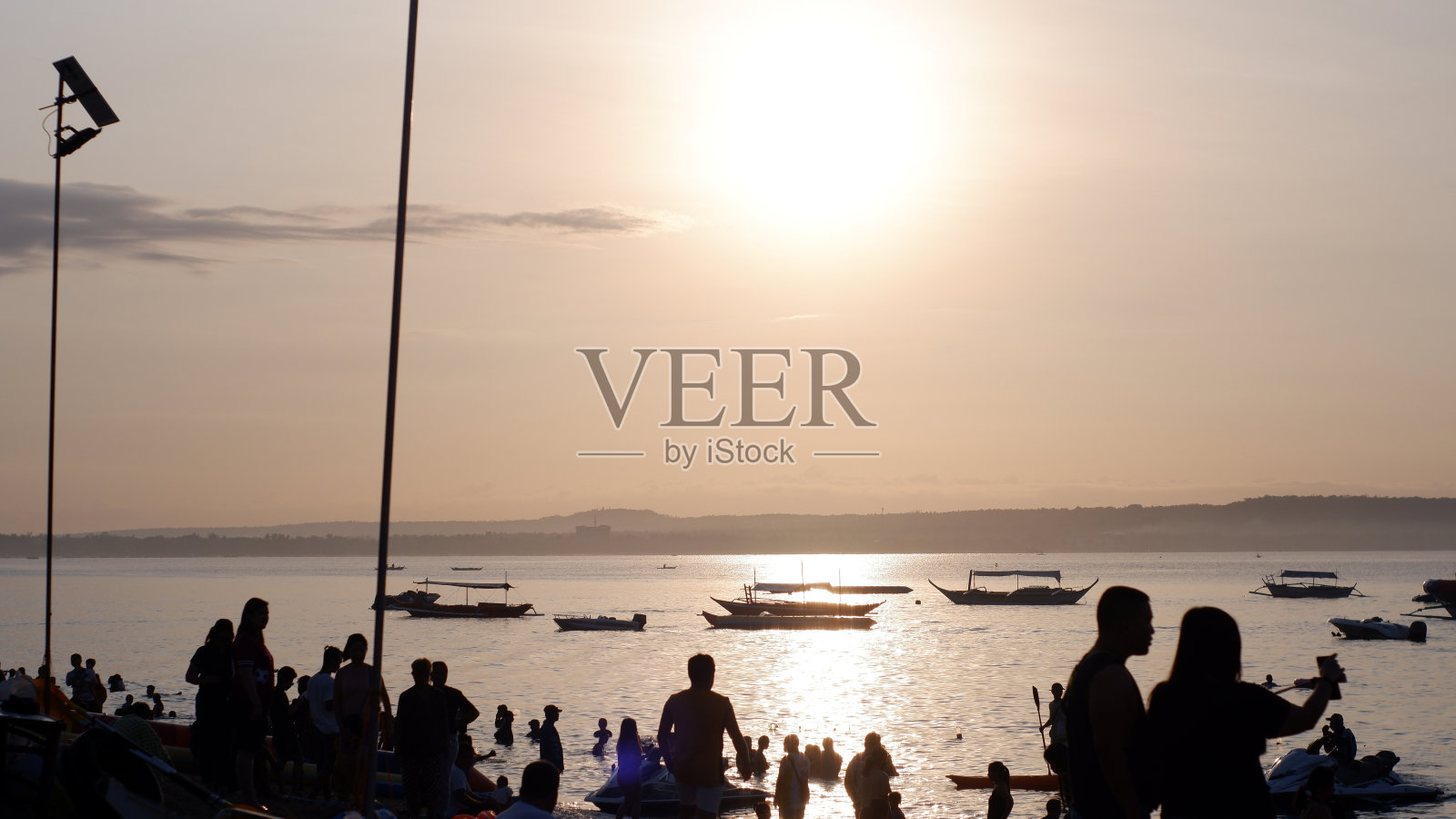 在炎热的夏天，面目不清的年轻人喜欢在浅水区游泳。照片摄影图片