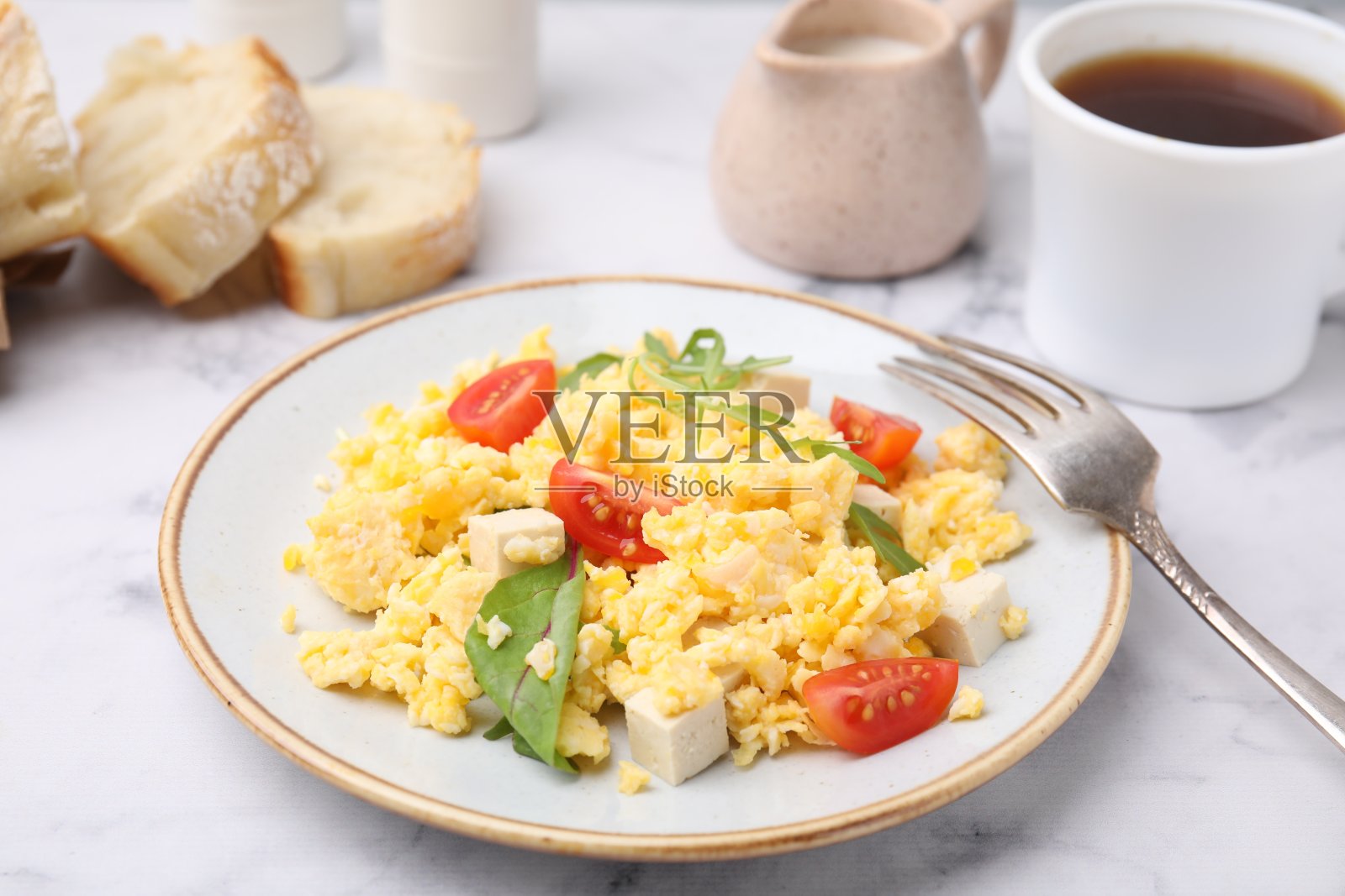 白色大理石桌上有美味的炒鸡蛋、豆腐和西红柿照片摄影图片