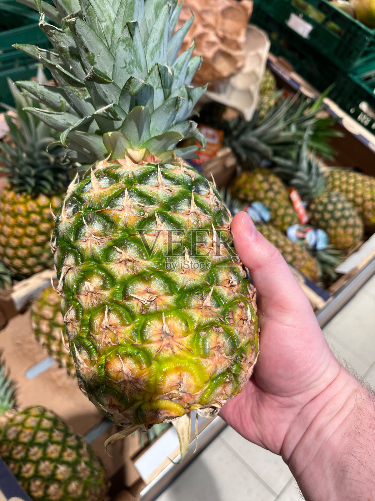 在杂货店，新鲜的菠萝在手照片摄影图片