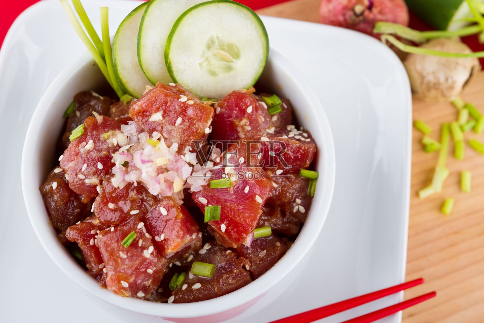 一盘刚准备好的Poke Bowls，放在木板上，旁边放上筷子照片摄影图片