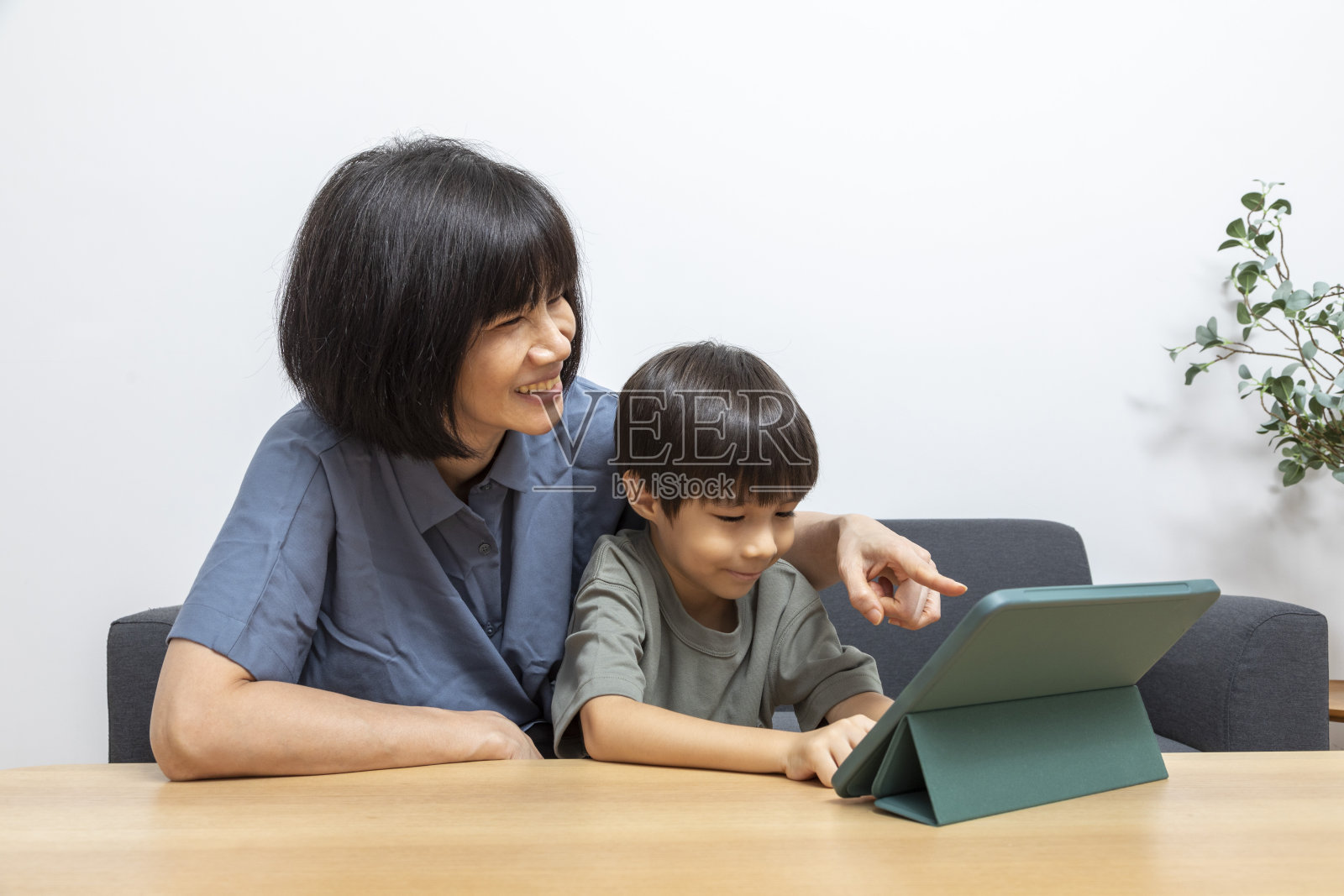 快乐的亚洲家庭在客厅的沙发上与数码平板电脑共度时光。照片摄影图片