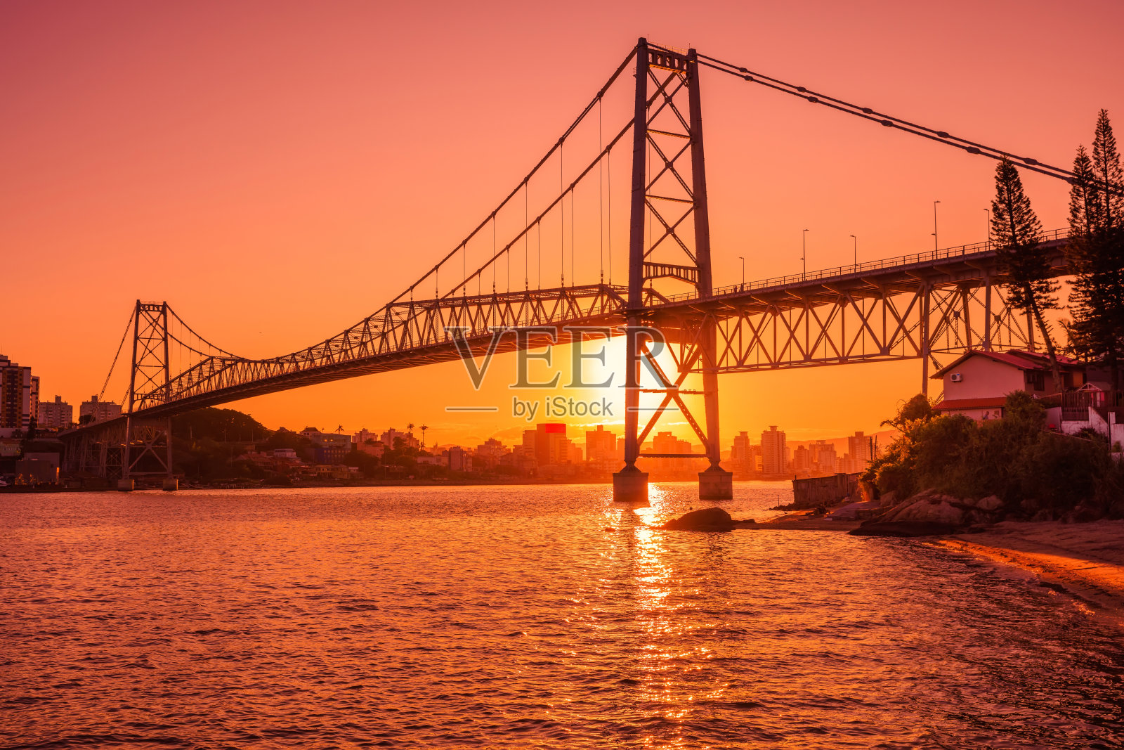 在弗洛里亚诺波利斯，Hercilio luz老桥上有温暖的日落和水面上的倒影照片摄影图片