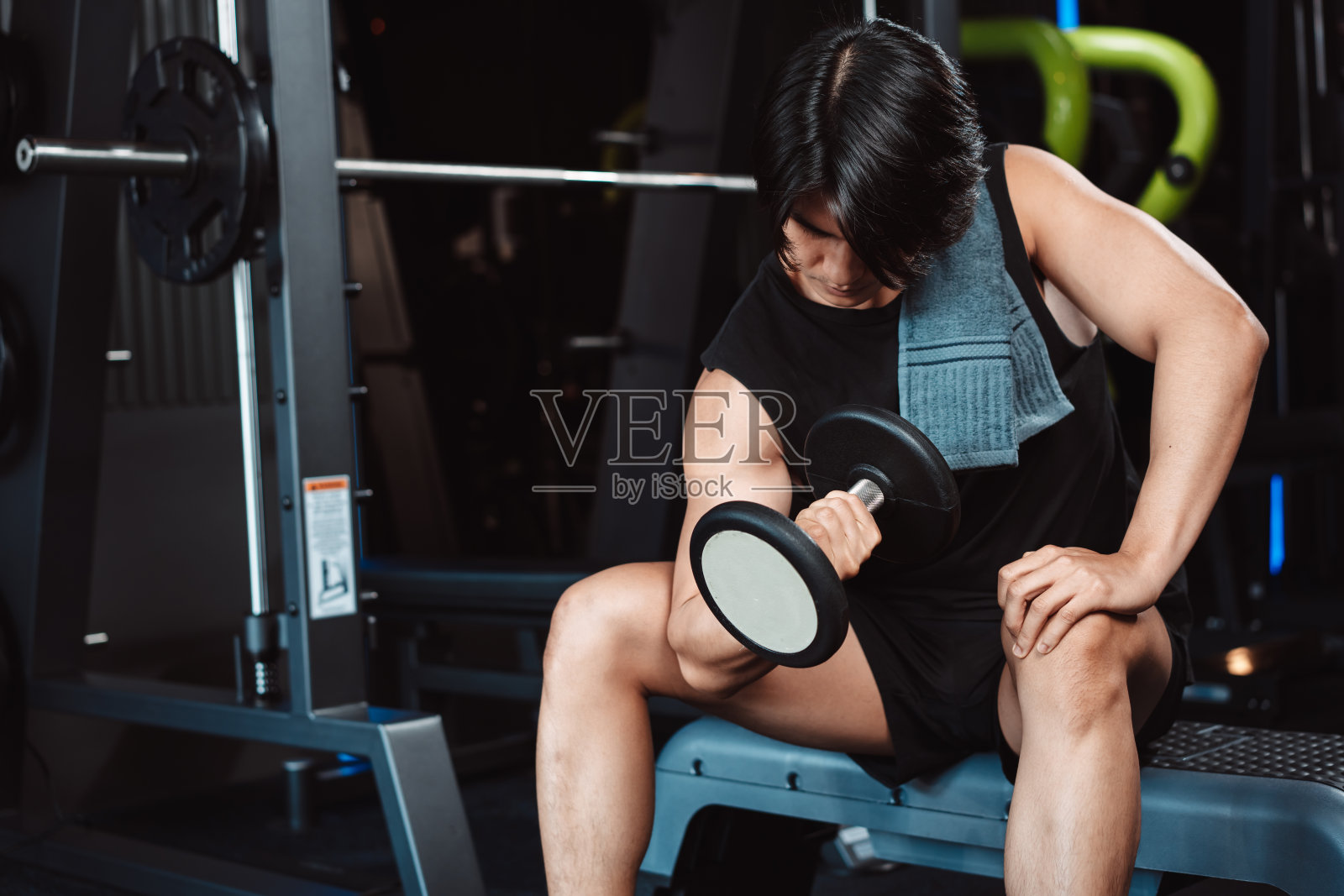 男健美运动员在健身房用哑铃举重。男健美运动员用哑铃做运动。训练运动健康生活方式健美，运动员健美肌肉生活方式。照片摄影图片