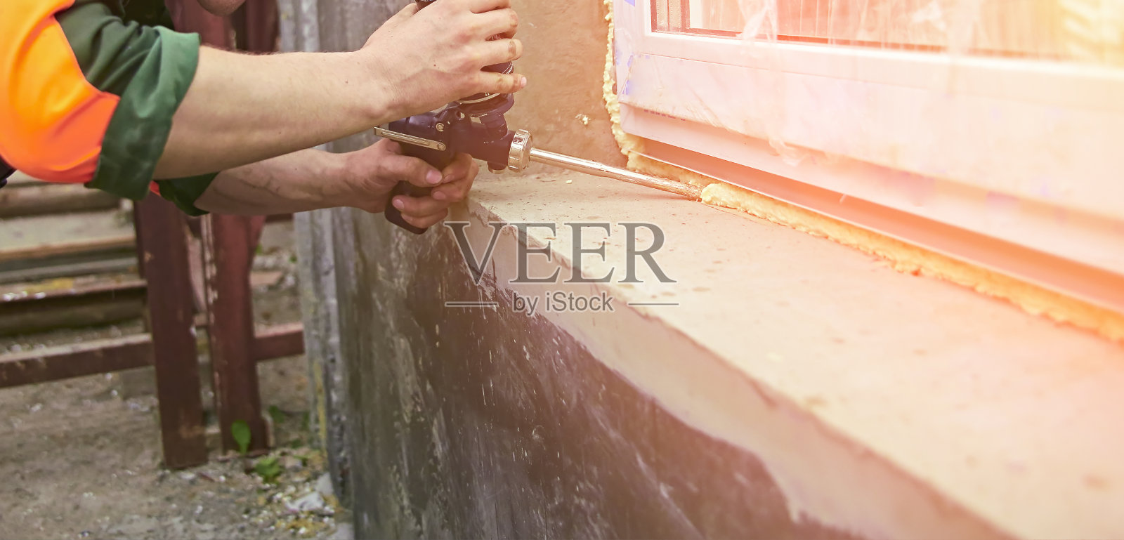 一名建筑工人将密封泡沫胶带粘在房子的窗户上。照片摄影图片