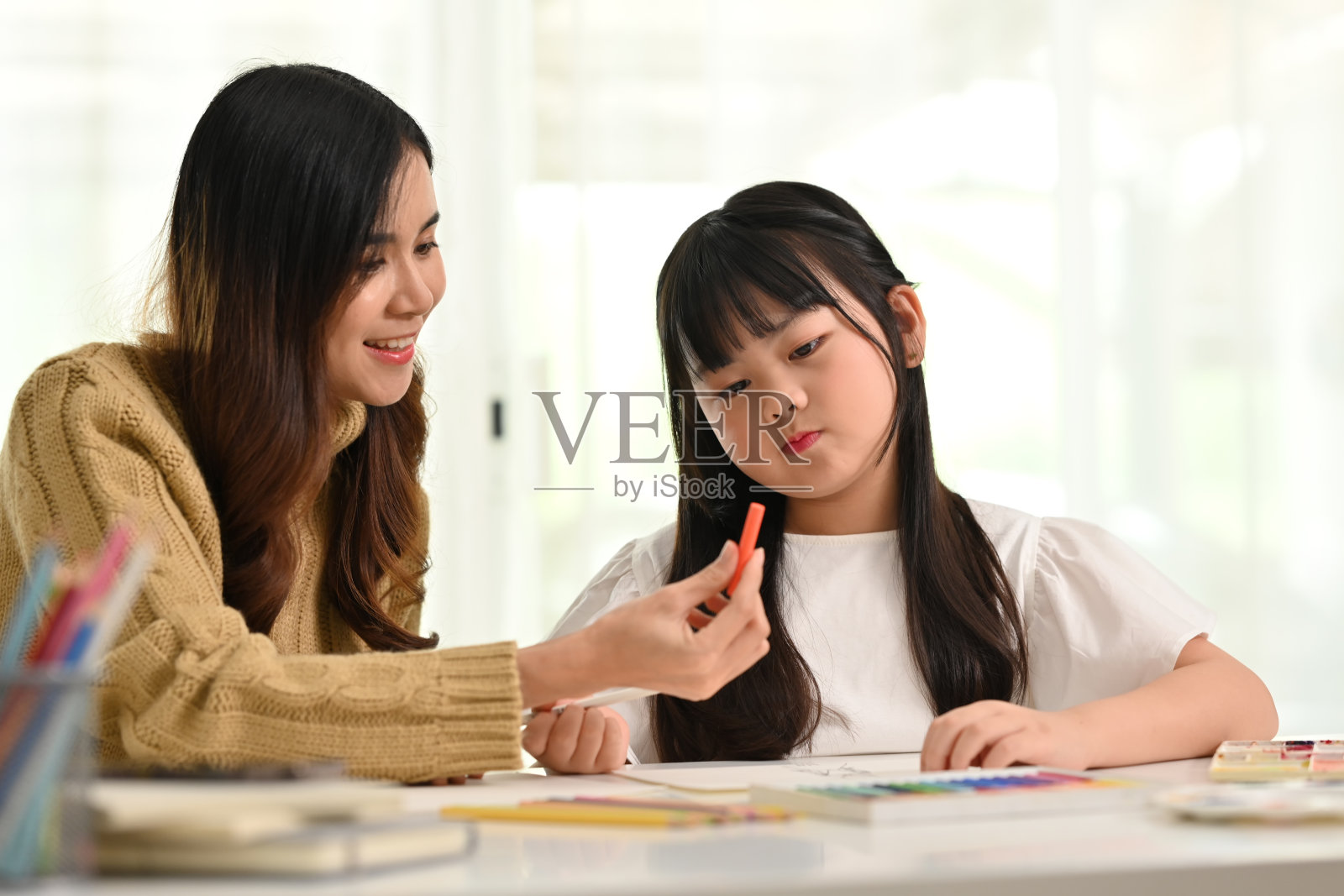 年轻的母亲在家帮助女儿做创意艺术作业。在家上学，学习和家庭观念。照片摄影图片